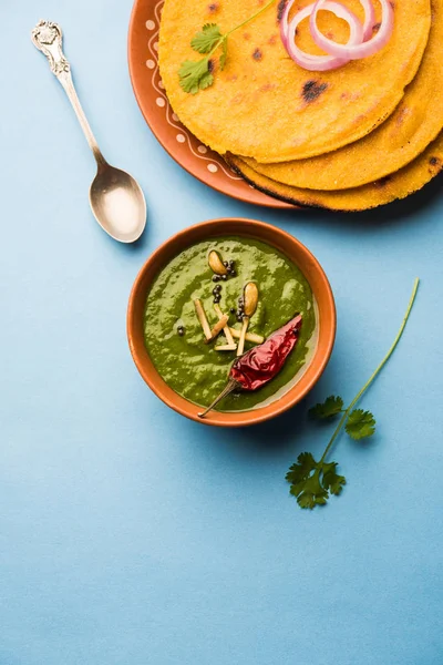 Makki di roti with sarson ka saag, popular punjabi main course recipe in winters made using corn breads mustard leaves curry. served over moody background. selective focus