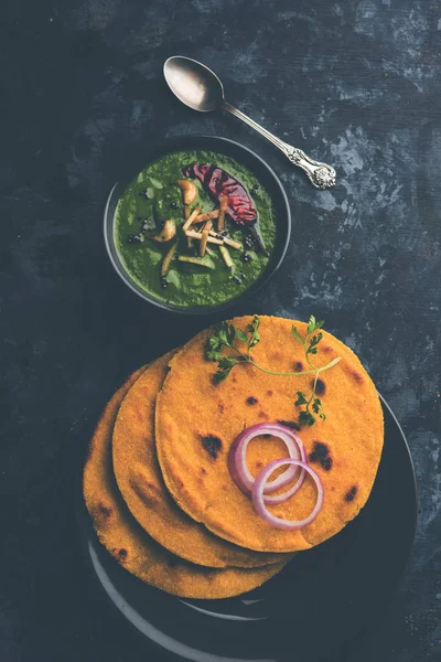 Makki di roti with sarson ka saag, popular punjabi main course recipe in winters made using corn breads mustard leaves curry. served over moody background. selective focus