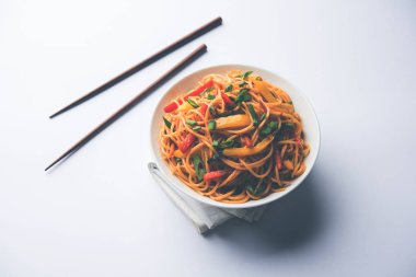 Schezwan erişte veya sebze Hakka erişte veya chow mein tahta çubukla bir kase veya plaka servis popüler Hint-Çin yemek tarifleri, var. seçici odak