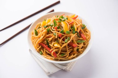 Schezwan erişte veya sebze Hakka erişte veya chow mein tahta çubukla bir kase veya plaka servis popüler Hint-Çin yemek tarifleri, var. seçici odak