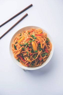 Schezwan erişte veya sebze Hakka erişte veya chow mein tahta çubukla bir kase veya plaka servis popüler Hint-Çin yemek tarifleri, var. seçici odak