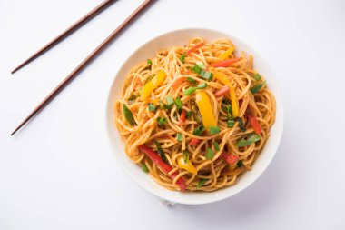 Schezwan erişte veya sebze Hakka erişte veya chow mein tahta çubukla bir kase veya plaka servis popüler Hint-Çin yemek tarifleri, var. seçici odak