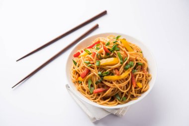 Schezwan erişte veya sebze Hakka erişte veya chow mein tahta çubukla bir kase veya plaka servis popüler Hint-Çin yemek tarifleri, var. seçici odak