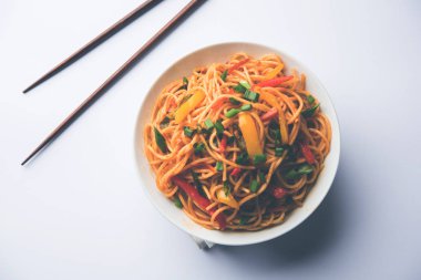 Schezwan erişte veya sebze Hakka erişte veya chow mein tahta çubukla bir kase veya plaka servis popüler Hint-Çin yemek tarifleri, var. seçici odak