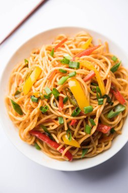 Schezwan erişte veya sebze Hakka erişte veya chow mein tahta çubukla bir kase veya plaka servis popüler Hint-Çin yemek tarifleri, var. seçici odak