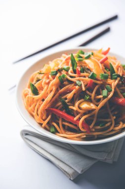 Schezwan erişte veya sebze Hakka erişte veya chow mein tahta çubukla bir kase veya plaka servis popüler Hint-Çin yemek tarifleri, var. seçici odak