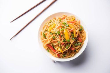 Schezwan erişte veya sebze Hakka erişte veya chow mein tahta çubukla bir kase veya plaka servis popüler Hint-Çin yemek tarifleri, var. seçici odak