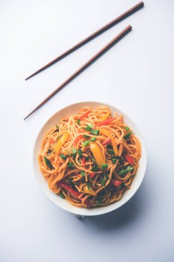 Schezwan erişte veya sebze Hakka erişte veya chow mein tahta çubukla bir kase veya plaka servis popüler Hint-Çin yemek tarifleri, var. seçici odak