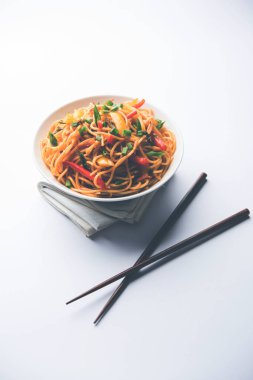 Schezwan erişte veya sebze Hakka erişte veya chow mein tahta çubukla bir kase veya plaka servis popüler Hint-Çin yemek tarifleri, var. seçici odak