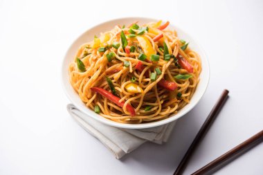Schezwan erişte veya sebze Hakka erişte veya chow mein tahta çubukla bir kase veya plaka servis popüler Hint-Çin yemek tarifleri, var. seçici odak