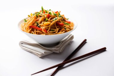 Schezwan erişte veya sebze Hakka erişte veya chow mein tahta çubukla bir kase veya plaka servis popüler Hint-Çin yemek tarifleri, var. seçici odak