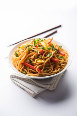 Schezwan erişte veya sebze Hakka erişte veya chow mein tahta çubukla bir kase veya plaka servis popüler Hint-Çin yemek tarifleri, var. seçici odak