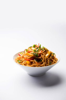 Schezwan erişte veya sebze Hakka erişte veya chow mein tahta çubukla bir kase veya plaka servis popüler Hint-Çin yemek tarifleri, var. seçici odak