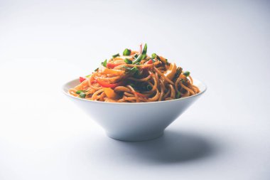 Schezwan erişte veya sebze Hakka erişte veya chow mein tahta çubukla bir kase veya plaka servis popüler Hint-Çin yemek tarifleri, var. seçici odak