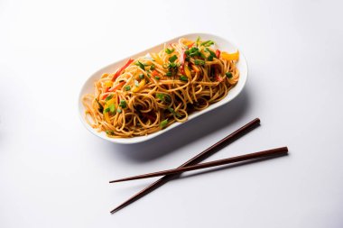 Schezwan erişte veya sebze Hakka erişte veya chow mein tahta çubukla bir kase veya plaka servis popüler Hint-Çin yemek tarifleri, var. seçici odak