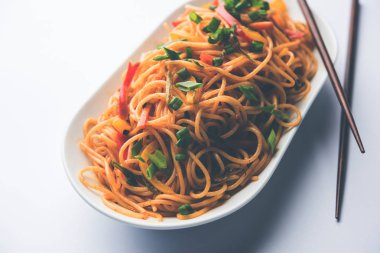 Schezwan erişte veya sebze Hakka erişte veya chow mein tahta çubukla bir kase veya plaka servis popüler Hint-Çin yemek tarifleri, var. seçici odak