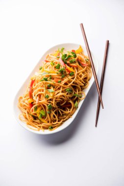 Schezwan erişte veya sebze Hakka erişte veya chow mein tahta çubukla bir kase veya plaka servis popüler Hint-Çin yemek tarifleri, var. seçici odak