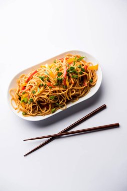 Schezwan erişte veya sebze Hakka erişte veya chow mein tahta çubukla bir kase veya plaka servis popüler Hint-Çin yemek tarifleri, var. seçici odak