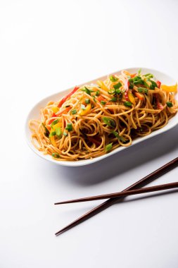 Schezwan erişte veya sebze Hakka erişte veya chow mein tahta çubukla bir kase veya plaka servis popüler Hint-Çin yemek tarifleri, var. seçici odak