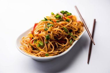 Schezwan erişte veya sebze Hakka erişte veya chow mein tahta çubukla bir kase veya plaka servis popüler Hint-Çin yemek tarifleri, var. seçici odak