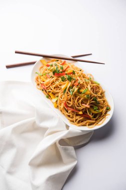 Schezwan erişte veya sebze Hakka erişte veya chow mein tahta çubukla bir kase veya plaka servis popüler Hint-Çin yemek tarifleri, var. seçici odak