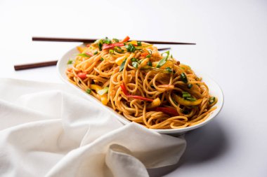 Schezwan erişte veya sebze Hakka erişte veya chow mein tahta çubukla bir kase veya plaka servis popüler Hint-Çin yemek tarifleri, var. seçici odak