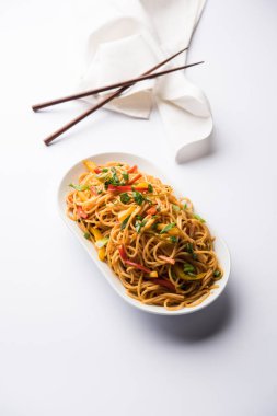 Schezwan erişte veya sebze Hakka erişte veya chow mein tahta çubukla bir kase veya plaka servis popüler Hint-Çin yemek tarifleri, var. seçici odak