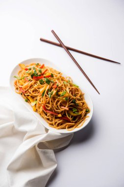 Schezwan erişte veya sebze Hakka erişte veya chow mein tahta çubukla bir kase veya plaka servis popüler Hint-Çin yemek tarifleri, var. seçici odak