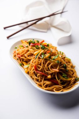 Schezwan erişte veya sebze Hakka erişte veya chow mein tahta çubukla bir kase veya plaka servis popüler Hint-Çin yemek tarifleri, var. seçici odak