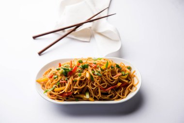 Schezwan erişte veya sebze Hakka erişte veya chow mein tahta çubukla bir kase veya plaka servis popüler Hint-Çin yemek tarifleri, var. seçici odak