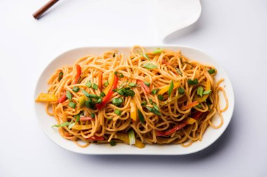 Schezwan erişte veya sebze Hakka erişte veya chow mein tahta çubukla bir kase veya plaka servis popüler Hint-Çin yemek tarifleri, var. seçici odak