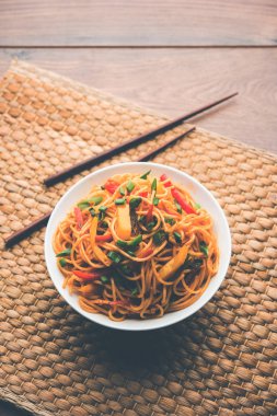 Schezwan erişte veya sebze Hakka erişte veya chow mein tahta çubukla bir kase veya plaka servis popüler Hint-Çin yemek tarifleri, var. seçici odak