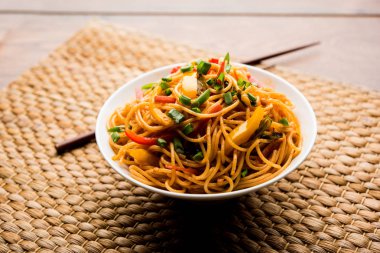 Schezwan erişte veya sebze Hakka erişte veya chow mein tahta çubukla bir kase veya plaka servis popüler Hint-Çin yemek tarifleri, var. seçici odak