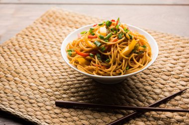 Schezwan erişte veya sebze Hakka erişte veya chow mein tahta çubukla bir kase veya plaka servis popüler Hint-Çin yemek tarifleri, var. seçici odak