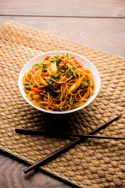 Schezwan erişte veya sebze Hakka erişte veya chow mein tahta çubukla bir kase veya plaka servis popüler Hint-Çin yemek tarifleri, var. seçici odak