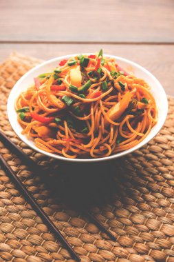 Schezwan erişte veya sebze Hakka erişte veya chow mein tahta çubukla bir kase veya plaka servis popüler Hint-Çin yemek tarifleri, var. seçici odak