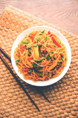 Schezwan erişte veya sebze Hakka erişte veya chow mein tahta çubukla bir kase veya plaka servis popüler Hint-Çin yemek tarifleri, var. seçici odak