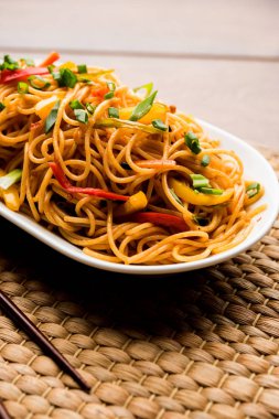 Schezwan erişte veya sebze Hakka erişte veya chow mein tahta çubukla bir kase veya plaka servis popüler Hint-Çin yemek tarifleri, var. seçici odak