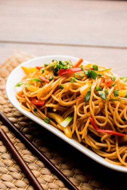 Schezwan erişte veya sebze Hakka erişte veya chow mein tahta çubukla bir kase veya plaka servis popüler Hint-Çin yemek tarifleri, var. seçici odak