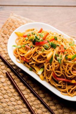 Schezwan erişte veya sebze Hakka erişte veya chow mein tahta çubukla bir kase veya plaka servis popüler Hint-Çin yemek tarifleri, var. seçici odak