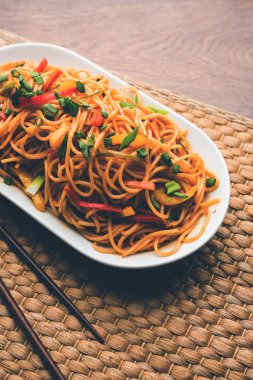 Schezwan erişte veya sebze Hakka erişte veya chow mein tahta çubukla bir kase veya plaka servis popüler Hint-Çin yemek tarifleri, var. seçici odak