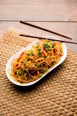 Schezwan erişte veya sebze Hakka erişte veya chow mein tahta çubukla bir kase veya plaka servis popüler Hint-Çin yemek tarifleri, var. seçici odak