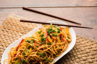 Schezwan erişte veya sebze Hakka erişte veya chow mein tahta çubukla bir kase veya plaka servis popüler Hint-Çin yemek tarifleri, var. seçici odak