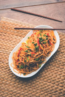 Schezwan erişte veya sebze Hakka erişte veya chow mein tahta çubukla bir kase veya plaka servis popüler Hint-Çin yemek tarifleri, var. seçici odak