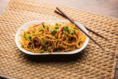 Schezwan erişte veya sebze Hakka erişte veya chow mein tahta çubukla bir kase veya plaka servis popüler Hint-Çin yemek tarifleri, var. seçici odak