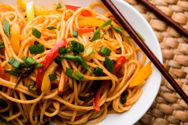Schezwan erişte veya sebze Hakka erişte veya chow mein tahta çubukla bir kase veya plaka servis popüler Hint-Çin yemek tarifleri, var. seçici odak