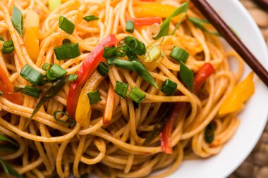 Schezwan erişte veya sebze Hakka erişte veya chow mein tahta çubukla bir kase veya plaka servis popüler Hint-Çin yemek tarifleri, var. seçici odak