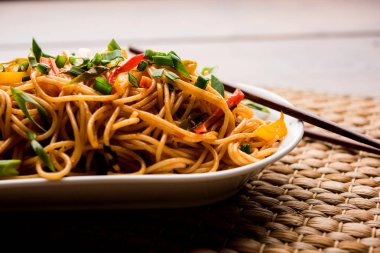 Schezwan erişte veya sebze Hakka erişte veya chow mein tahta çubukla bir kase veya plaka servis popüler Hint-Çin yemek tarifleri, var. seçici odak