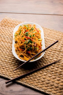 Schezwan erişte veya sebze Hakka erişte veya chow mein tahta çubukla bir kase veya plaka servis popüler Hint-Çin yemek tarifleri, var. seçici odak