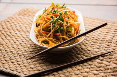 Schezwan erişte veya sebze Hakka erişte veya chow mein tahta çubukla bir kase veya plaka servis popüler Hint-Çin yemek tarifleri, var. seçici odak